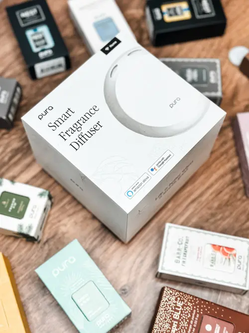 Pura Smart Fragrance Diffuser surrounded by fragrance refills